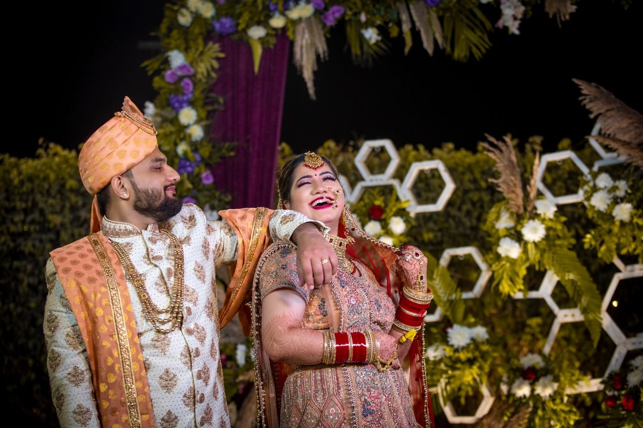 our-story-01 A joyful Indian bride and groom celebrate their wedding adorned in traditional attire.