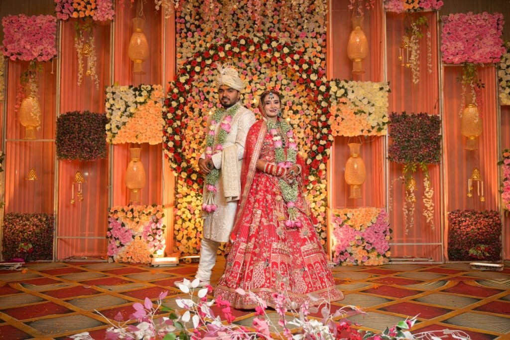 Elegant Indian couple posing at their wedding ceremony with floral decor background.